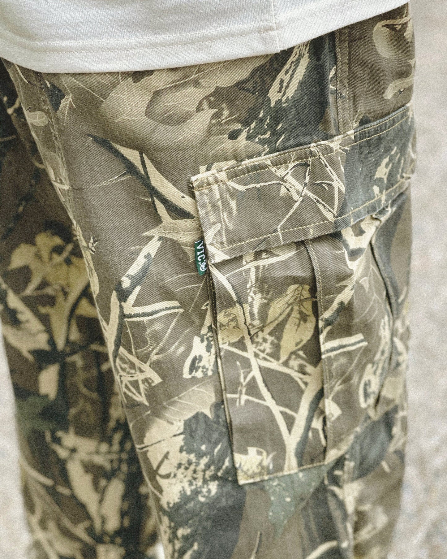 Realtree Camo Cargo Pant - Vintage Streetwear Military Army Style  Elevate your streetwear with our Realtree Camo Cargo Pants. These vintage-style pants feature a relaxed fit, low waist, and are made from 100% cotton. They offer extra durability with a double-layer knee, slightly tapered leg, and drawstring cuffs. Perfect for urban adventurers and military enthusiasts, these camo pants blend style and functionality seamlessly.