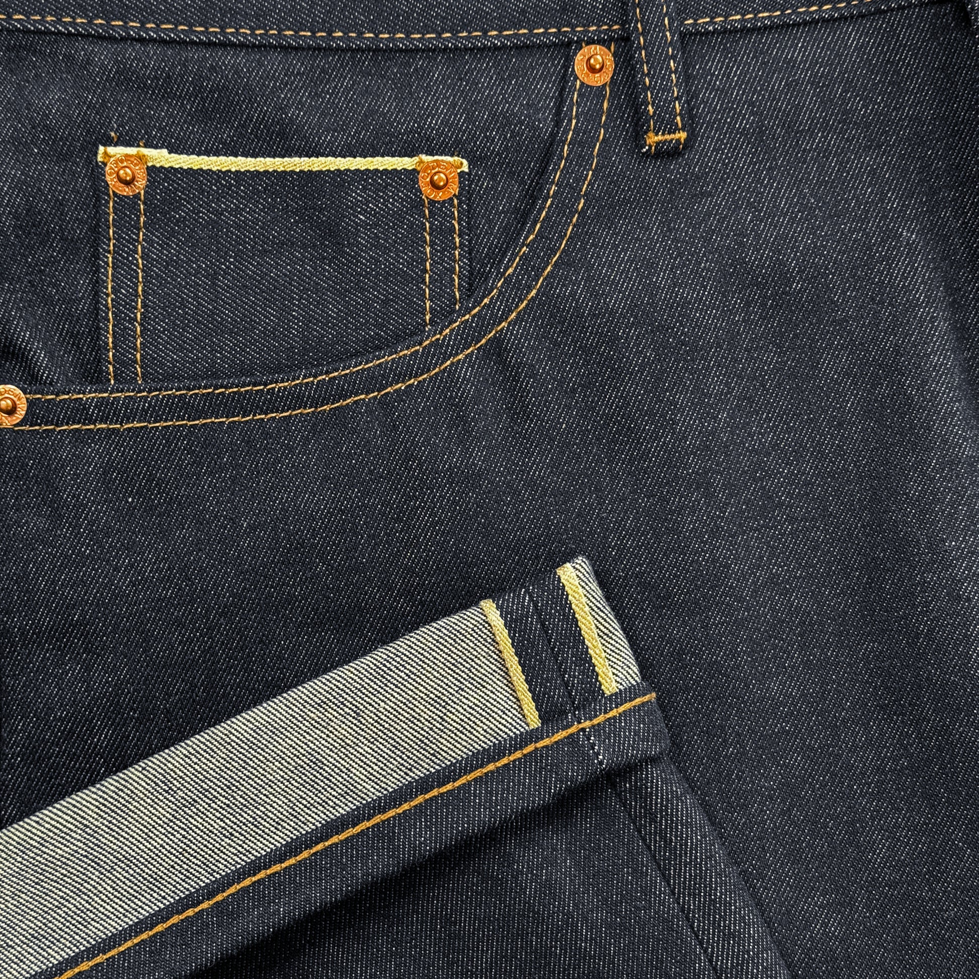 RAW SELVEDGE JEANS in dark indigo with a regular straight leg fit, cut from premium 15oz raw selvedge denim. Finished with contrast stitching, selvedge detail on the coin pocket, and a VIC woven patch on the waistband. Inspired by vintage Japanese selvedge denim and reimagined with a modern silhouette.